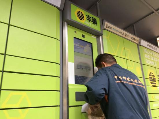 图/一名快递员正在往丰巢快递柜投递快递。罗晓兰摄