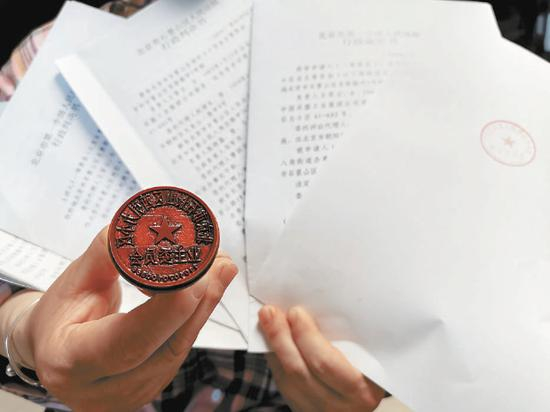 西引力小区原业委会成员展示其仍妥善保存的公章及胜诉判决