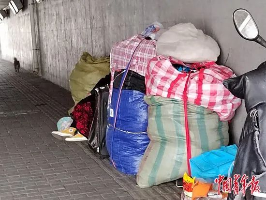 六里桥的桥洞下，堆放着一些编织袋，一位女性农民工坐在中间休息，被挡住了脸。