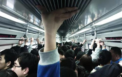 　拥挤的早高峰车厢里双手无处把扶的乘客将手支撑在车顶上。（2014年3月28日摄）