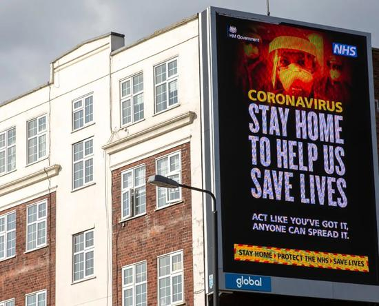 4月3日，在英国伦敦，电子屏幕显示劝导人们不要出门的宣传口号。（图片来源：新华社记者 韩岩 摄）