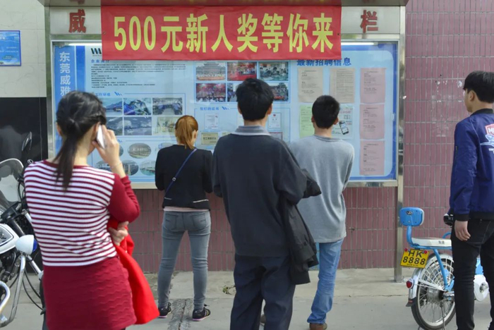 2017年2月6日，春节后，东莞的打工者在工厂门口查看工厂的招聘信息（摄影/占有兵）