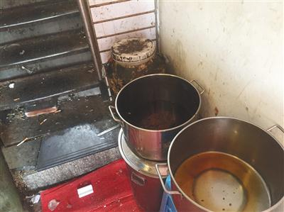 “有饭炸鸡”店铺旁狭窄过道内，潲水桶、盛着油渣的圆桶、面粉等堆在一起，地上散落着烟头、卫生纸、砖块。新京报记者&nbsp;张越摄