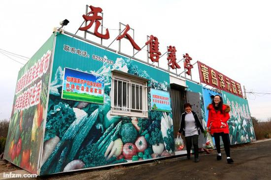 山东即墨，两名顾客购买蔬菜后离开“无人售菜亭”。开业以来，这种即摘即卖、零距离供货、自助选择交费的消费模式被周边顾客所接受，收款箱内如数收回了菜金，菜亭日营业额也由开业时的1000余元，逐渐上升到3000余元。（东方IC/图）