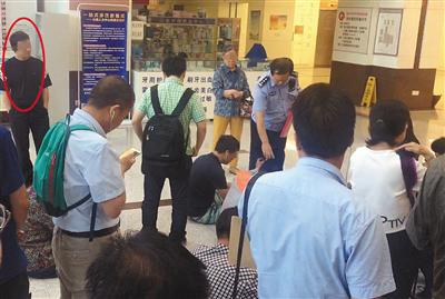 挂号大厅，一名号贩子（圆圈处）被民警认出，让其站在一边，等待被带离。&nbsp;