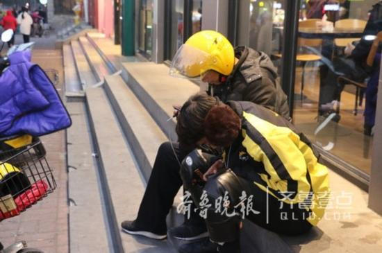 两位外卖小哥在台阶上等活