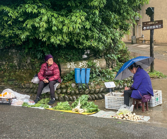 在明月村的村道旁卖竹笋、青菜、耙耙柑的村民。摄影/《财经》记者 邹碧颖