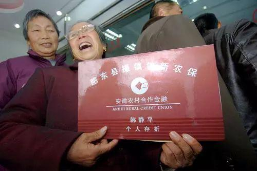  2010年2月8日，在安徽合肥市肥东县撮镇农村合作银行内，农民韩静平（中）展示新型农村社会养老金纪念存折。图源：新华社|郭晨