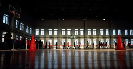 1月11日，辽宁沈阳市铁西区，人们在彰驿学校检测点排队等待核酸采样。图/新华