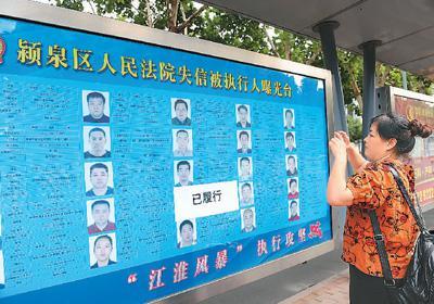 　　2018年6月21日，安徽省阜阳市清河路一公交站台上晒失信被执行人名单，吸引群众目光。王 彪摄（人民视觉）