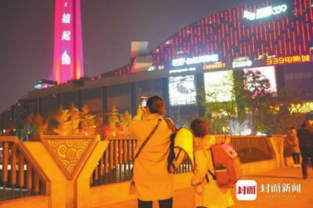 2019年12月9日，成都天府熊猫塔为电竞战队助威的灯光引得市民驻足拍摄。