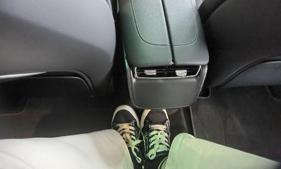 ▲试乘者坐在EQE后排中间座椅，难以落脚