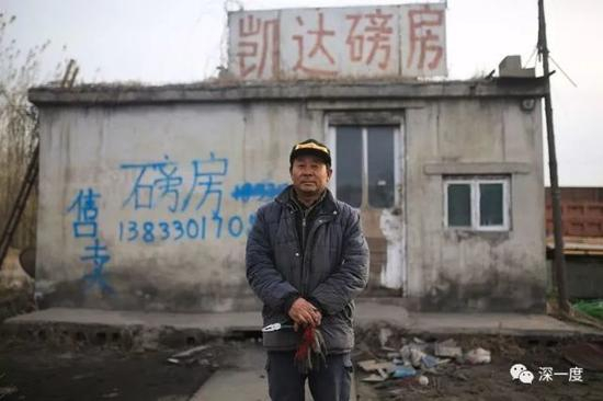 △ 陈永拴站在自家煤厂的磅房前，磅房上也写上了售卖的信息