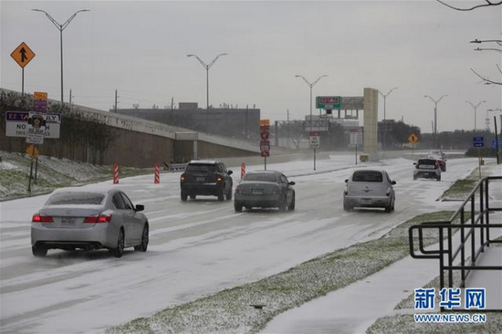 2月15日，在美国得克萨斯州休斯敦，车辆在积雪的道路上行驶。图片来源：新华社