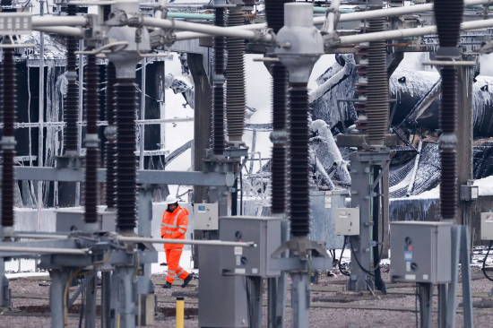 3 月 21 日，在伦敦西部海斯，一名工作人员走过为希思罗机场供电且发生火灾的变电站。