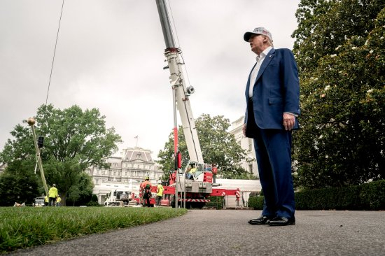 6月18日，唐纳德·特朗普在华盛顿特区白宫南草坪上与媒体成员交谈，工人们正在安装一座新旗杆。