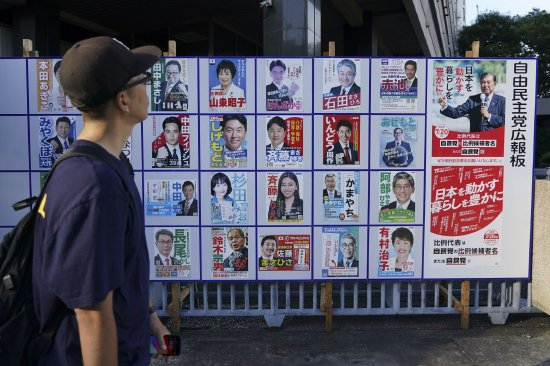 7 月 20 日，东京，一名行人看着自民党候选人与石破茂（右）的海报。