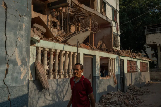 委内瑞拉拉瓜伊拉，一名男子走过一栋在美军军事干预中遭火箭弹袭击的公寓楼。