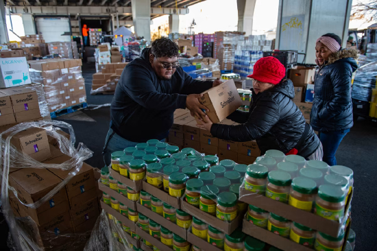 在美国马萨诸塞州切尔西市的 “合作组织” 食品分发站，工作人员和志愿者正整理捐赠的食品，准备分发给有需要的人。