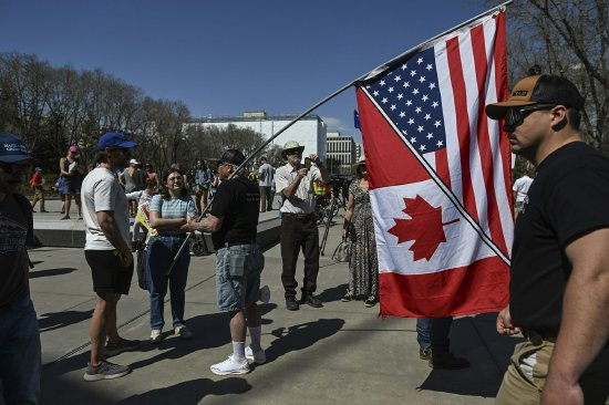 在埃德蒙顿，阿尔伯塔主权主义者聚集在省议会外，一名参与者挥舞着美国加拿大混合国旗。