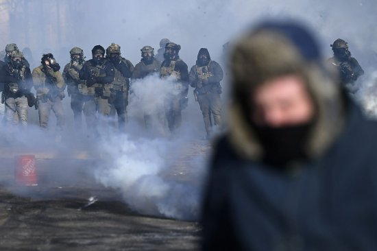 1月24日，在明尼阿波利斯，联邦特工在催泪瓦斯驱散抗议者时用武器指着他们。