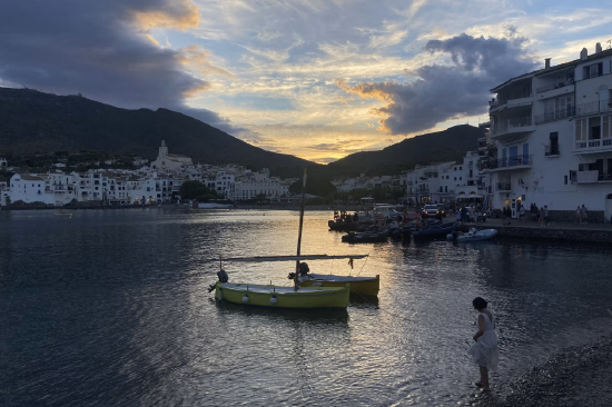 西班牙卡达克斯港口的日落时分，一名女子站在海中。