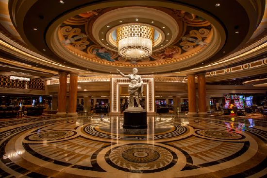 凯撒皇宫酒店及赌场主入口，中央矗立着尤利乌斯・凯撒巨型雕像，背景可见角子机。