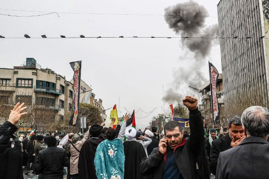 3月13日德黑兰，伊朗民众参加“古德斯日”游行时，空袭后浓烟升起。