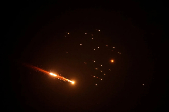 火箭火光划破漆黑夜空。周五新一轮伊朗导弹袭击来袭时，以色列沿海城市内坦亚上空的火箭轨迹。