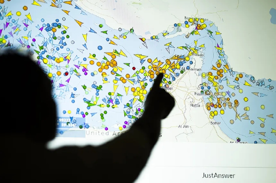2026 年 5 月 4 日示意图，一人站在大屏前查看船舶追踪网站上霍尔木兹海峡船只动态。