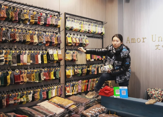 大唐袜业城里的年轻商贩在自己的摊位里摆放样品（缓山 摄）