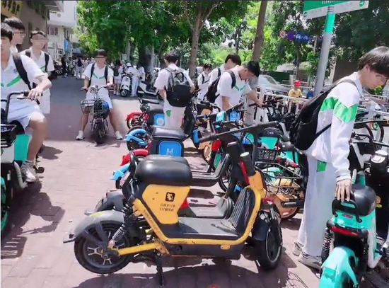 学生们纷纷扫码骑共享电动单车