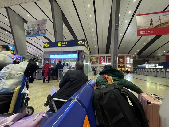 吴芳（右）正和候车室的人聊天 图源：时代周报记者摄