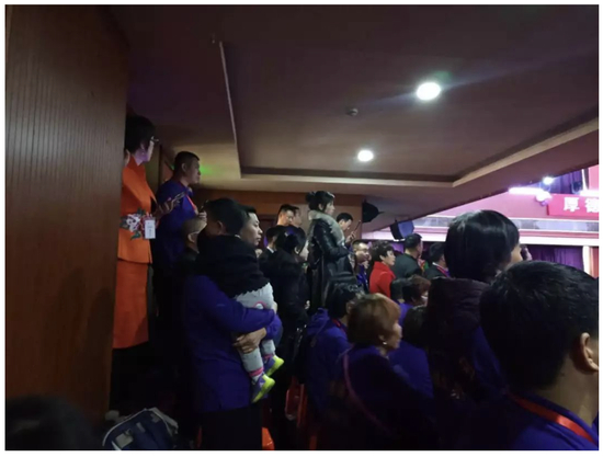 　　↑2000人的会场爆满，大量参会人员在后排添加塑料椅子就坐。图为抱孩子的参会人员站立参会。图片来源：每日经济新闻