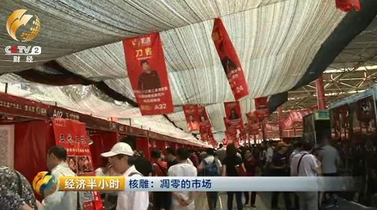 　　潘家园旧货市场的这块空地上，临时支起了一些棚子和摊位，正在举办一个核雕展销会。顶棚上方高高悬挂着前来参加展销会的雕刻师的照片。