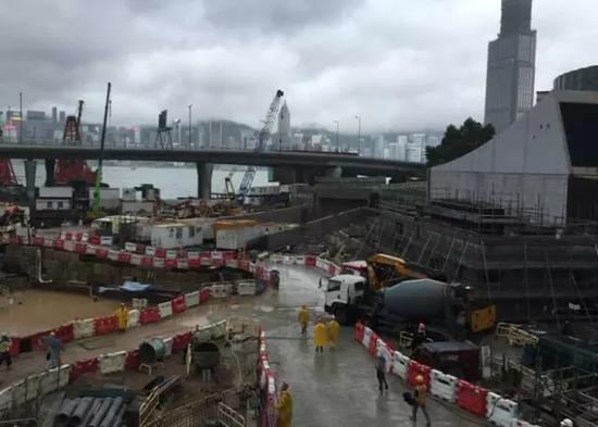 10月19日，香港维多利亚港附近的一处工地，工人披着雨衣准备开工