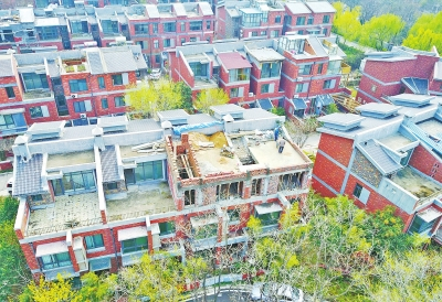 图中左下方的这排别墅中，右边两户加盖的房屋将要建好，左边两户的别墅还是原本交房的样子。