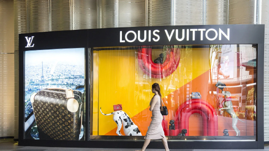 一名行人走过路威酩轩集团（LVMH Moët Hennessy Louis Vuitton SE）旗下路易威登（Louis Vuitton）门店的橱窗。