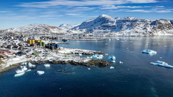 2025 年 3 月 11 日，格陵兰岛自治议会选举当日，努克海岸外，冰山漂浮在阳光照耀的海面上，背景可见沿岸建筑。格陵兰岛是丹麦的自治领地。