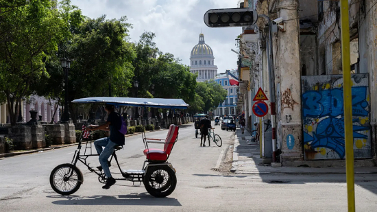 2026 年 3 月 4 日，哈瓦那，一辆三轮车驶过因停电而失灵的交通信号灯。