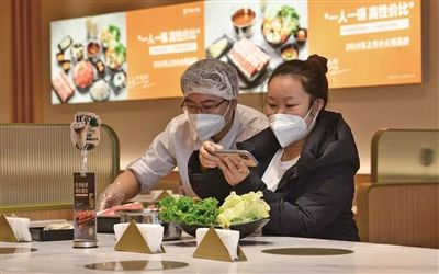 12月6日，呷哺呷哺餐厅，服务员为消费者上菜。受访者供图