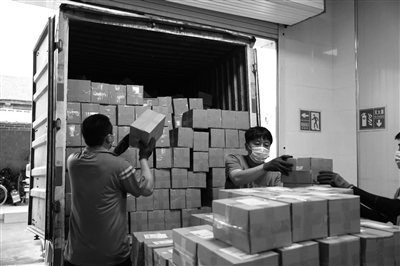 中通快递小哥正在将一个个擀面皮包裹装满车厢