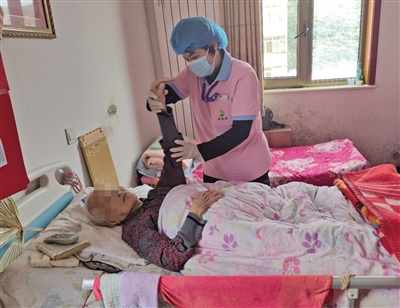 10月7日，秦姝颖为90岁的重度失能老人李淑英做肩关节被动活动。新京报记者 郭懿萌 摄