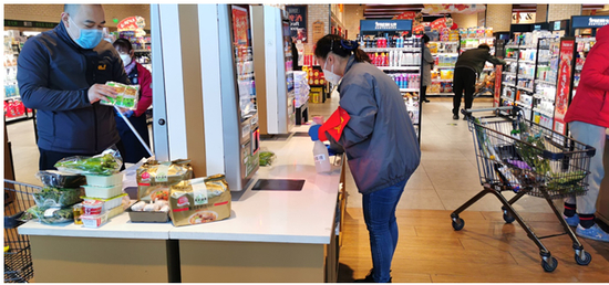 图注：保洁人员对无接触自助收银机进行消毒清洁