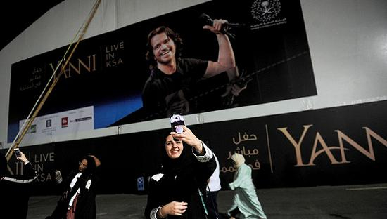 2017年11月30日，一名沙特女性在作曲家雅尼的音乐会海报前自拍。图片来源：视觉中国