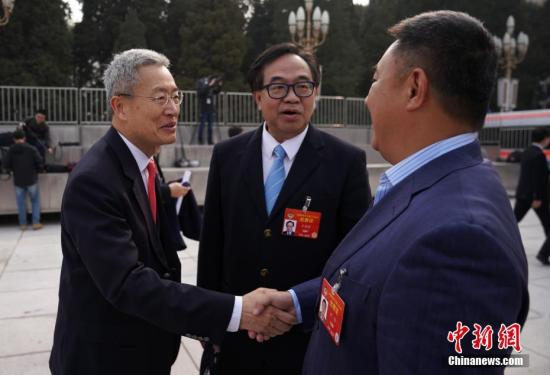 全国政协委员刘炳章（左）、卢伟国（中）、刘伟（右）在进入会场前就粤港澳大湾区进行交流。中新社记者 崔楠 摄