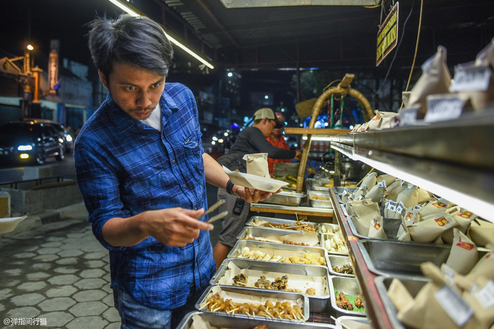 印尼夫妻档经营的路边摊,食客席地而吃,每天收入1000多万