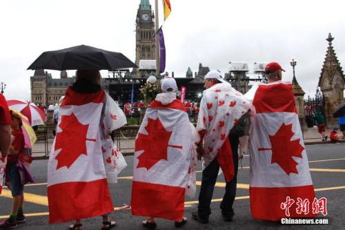 资料图片：加拿大联邦举行国庆庆典，民众身披加拿大国旗。中新社记者余瑞冬 摄