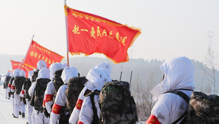 （图为哈尔滨市民兵高举“英雄旗”行进在冬训的林海雪原。孙健摄）