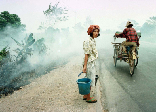 9月10日，苏门答腊岛，一名印尼妇女等待穿越从拉哈特到巴邻旁的道路。